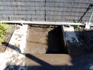 土を取り除いてみると下部はコンクリートで覆われ、小さな排水穴が開いた状態。しかも手前側は排水穴より深くなっているため、当然排水は充分に行われていない状態でした。